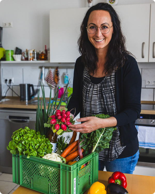 Kundin packt Obst und Gemüsebox in der Küche aus