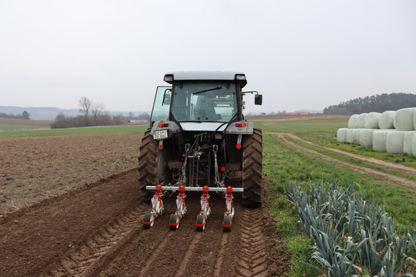 Traktor zieht Sämaschine über den Acker